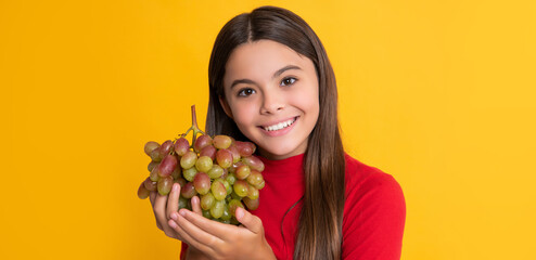 child smile hold fresh grapes fruit on yellow background