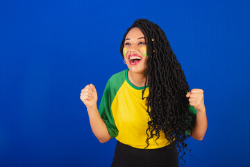 Young black Brazilian woman, soccer fan. celebrating and celebrating. Celebrating point, victory,...