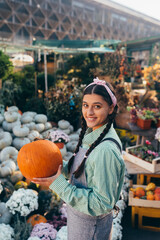 Fototapeta premium Happy farmer woman in a denim jumpsuit holds ripe pumpkin