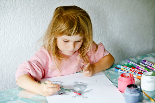Little creative toddler girl painting with finger colors koala bear. Active child having fun with drawing animals at home, in kindergaten or preschool. Education and distance learning for children