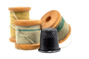An old wooden spool of thread and a needle on a white background close-up. Threads for sewing