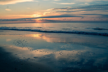 Sunrise on the beach with the sky reflecting on the wet sand
