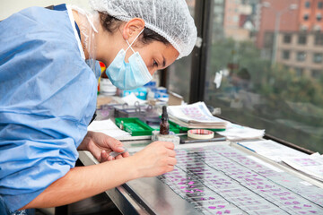 Young female scientist preparing slides with paraffin-embedded sections for pathological analysis .