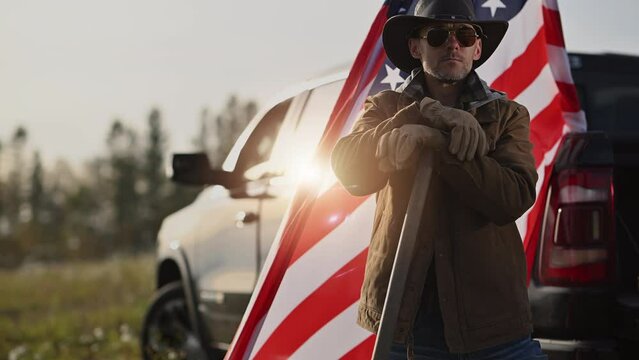Caucasian American Patiot Cowboy Farmer Staying  in Front of His Pickup Truck and American National Flag