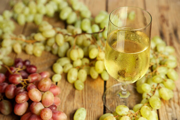glass of wine with grapes on wooden table