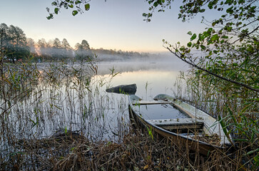Old rowboat in autumn foggy morning