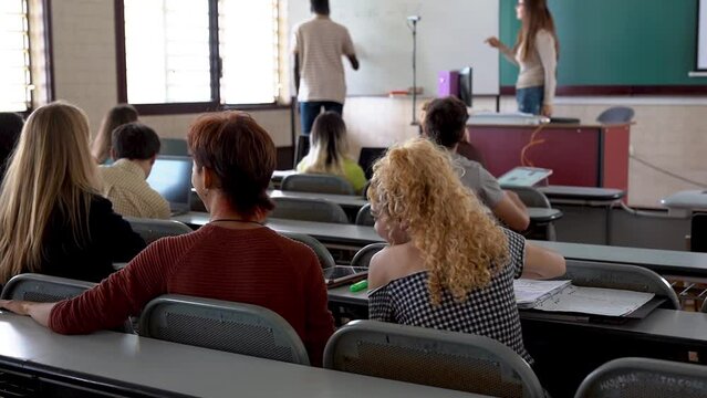 Young diverse people doing teamwork inside school university class room - Mature teacher working with multiracial students
