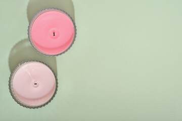 two wax candles over green background. fragrances for ambient home. natural coconut wax candles with floral scents. copy space. top view.