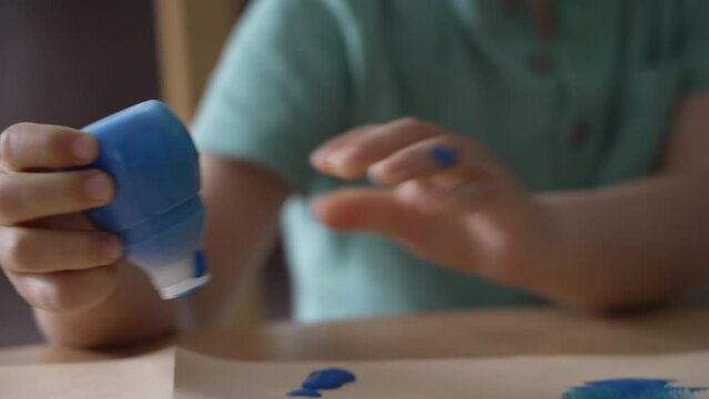 Child hands pressing coloring paint tube. Little boy using creativity activity closeup hand