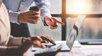 Young colleagues discuss business and analytical price charts using calculators and laptops to calculate financial, tax, accounting, statistics and analytical research ideas.