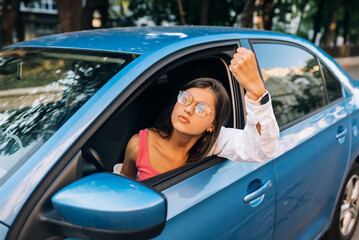 A young angry woman peeks out of the car window