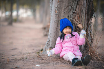 Portrait of cute asian little girl wear Winter clothes at the forest of the park,Thailand people pose for take a picture,Happy time