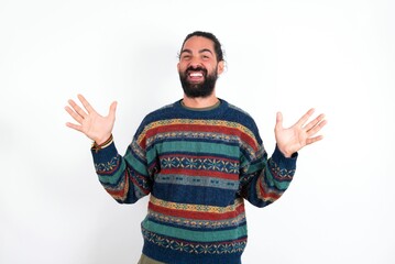 Fototapeta premium Crazy outraged Caucasian man with beard wearing sweater over white background screams loudly and gestures angrily yells furiously. Negative human emotions feelings concept