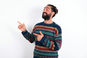 Fototapeta premium Caucasian man with beard wearing sweater over white background smile excited directing fingers look empty space