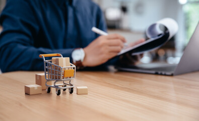 Cardboard box cargo on trolley on table in front of businessman, Online shopping and logistics of cargo and storage shipping business concept.