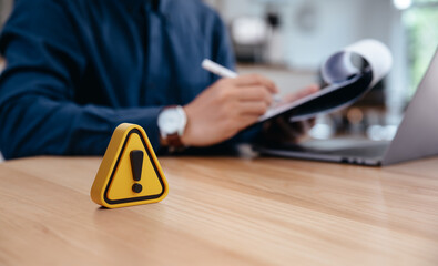 Warning sign on table in front of businessman Caution in investing Economic situation warning,...