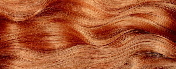 Red hair close-up as a background. Women's long orange hair. Beautifully styled wavy shiny curls....