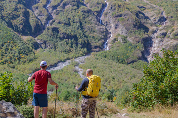 Fototapeta na wymiar Two tourists are going to climb up the mountain to the waterfalls, inspect the area.