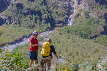 Two tourists are going to climb up the mountain to the waterfalls, inspect the area.