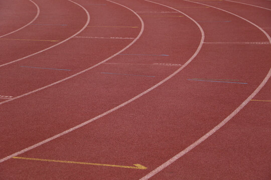 White lines forming lanes of an athletics track made of red rubber