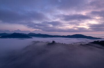 Cerkev Sveti Tomaž (St. Thomas Church) near Škofja Loka, Slovenia. Foggy morning and sunrise, drone photo