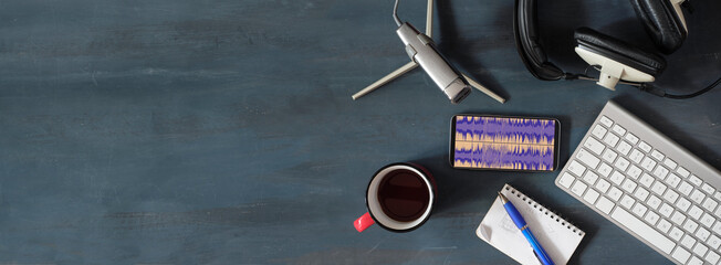 Music or podcast concept with stylish headphones,vintage microphone,coffee and computer keyboard on...