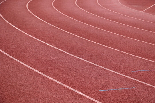 White lines forming lanes of an athletics track made of red rubber - Powered by Adobe