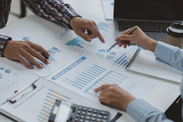 Financial analysts analyze business financial reports on a calculator planning investment project during a discussion at a meeting of corporate showing the results of their successful teamwork.	