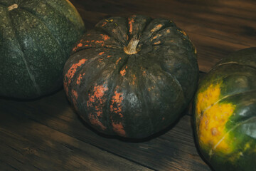 Three pumpkins stand in a row on a wooden table. Pumpkins for decorating the house on Halloween in...