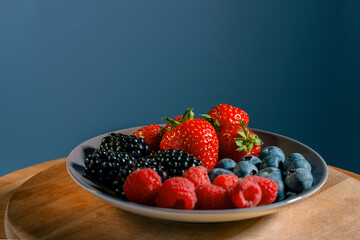 Berry mix of strawberries, blackberries, raspberries and blueberries on a blue background