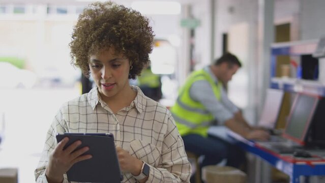 Female Manager In Logistics Distribution Warehouse Using Digital Tablet