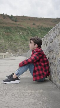 Sad teenager boy sitting on ground. Depression, anxiety, stress and loneliness concepts.