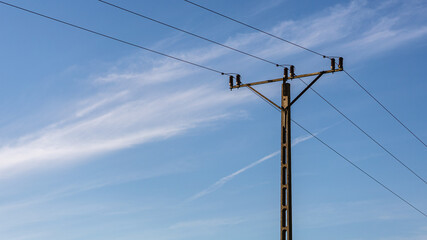 Minimalistic picture of electrical pole with cloudy sky in background