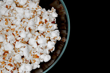 Fototapeta na wymiar Popcorn on a black background. Top view of the popcorn. Popcorn in a glass bowl
