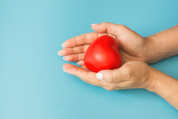 female hands hold toy heart blue background. The concept of life insurance, health protection, blood donation, donor day, human organs. Take care of your heart, mother's love