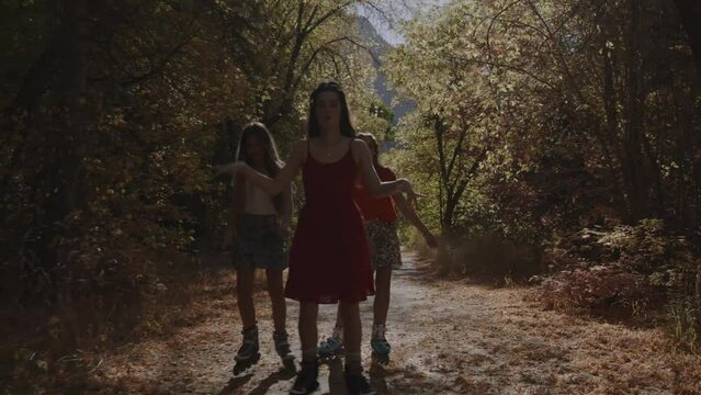 Carefree girls inline skating and listening to headphones on park path in autumn / American Fork Canyon, Utah, United States