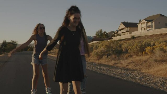 Carefree playful girls inline skating on park path / Cedar Hills, Utah, United States