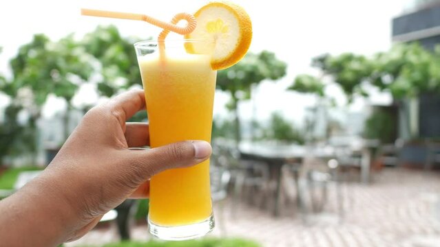 holding glass of orange juice outdoor 