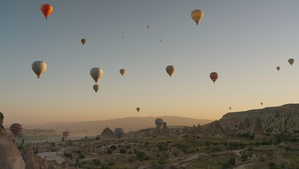 Many hot air balloons flying over Love valley early in morning in Cappadocia