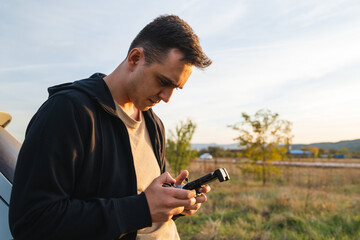 A man is operating a drone with a controller outside during the day