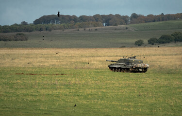 British army Challenger II 2 FV4034 main battle tank in action crossing open grass fields, on a...