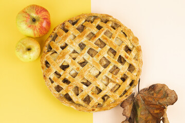 Baked apple pie with trellis decoration. Apples and dried leaves. Copy space.