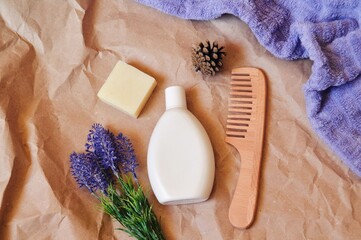 Flat lay beauty photo. White shampoo bottle, natural soap, wooden comb, purple towel and lavender...