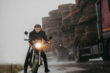 motorcyclist male biker on a foggy road with a motorcycle in autumn in rainy weather, the concept...