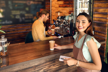 Beautiful business owner with notebook and cup of coffee in her cafe