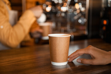 Young business owner with cup of coffee at table in her cafe, closeup