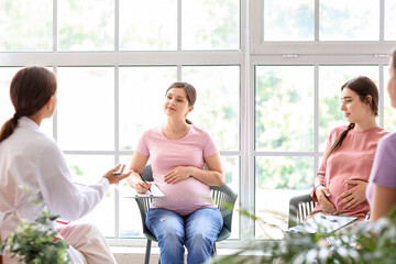Young pregnant women with clipboards at course for expectant mothers