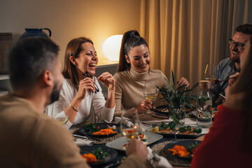 group of caucasian friends eating and talking at the home dinner party