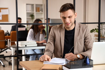 Young businessman with documents working at table in office