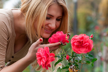 Portrait of a young woman with long blonde hair smelling a pink rose